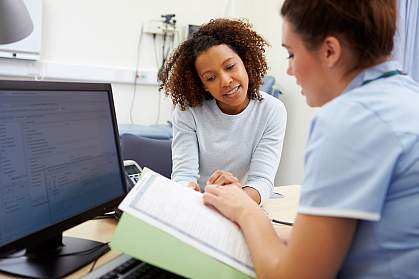 a photo of an African American woman and her female doctor discussing X-ray results