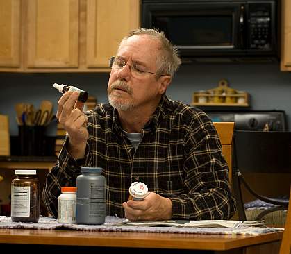 Photo of a man looking at a bottle of vitamins
