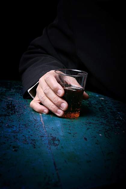 Photo of a hand holding a glass with an alcoholic drink