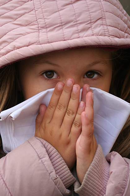 Photo of a child in a winter coat blowing her nose