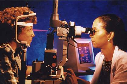 Photo of a female doctor performing laser eye therapy on a female patient