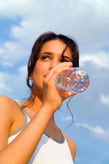 Photo of a woman drinking from a hard plastic water bottle