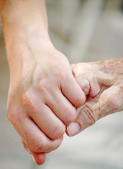 Photo of a young hand holding an elderly hand