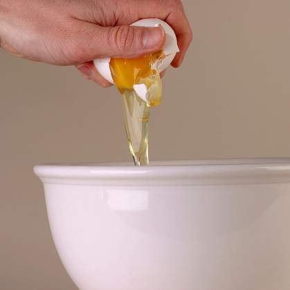 Photo of hand breaking egg into bowl