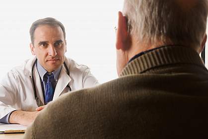 A photo of an older man consulting with his doctor