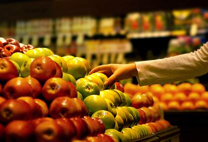 A photo of a hand picking up an apple at the supermarket