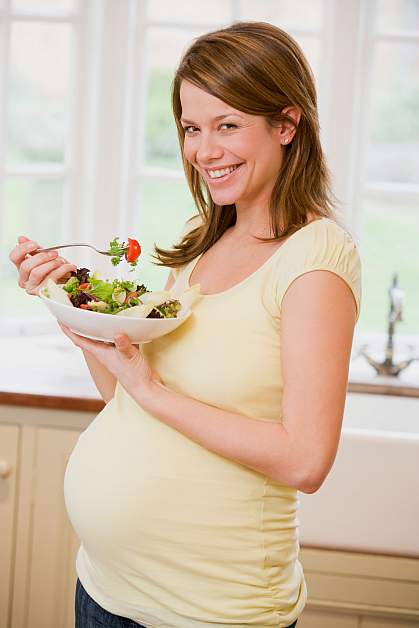 a photo of a pregnant woman eating a salad