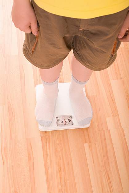 Photo of a boy standing on a bathroom scale