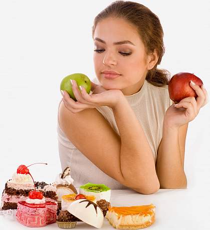 photo of a woman holding two apples but looking down at some sweets