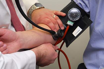 Photo of a doctor holding an arm in a blood pressure cuff