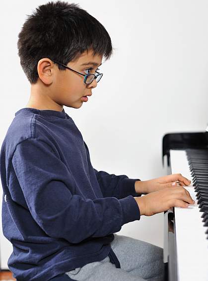 Photo of a boy playing a piano