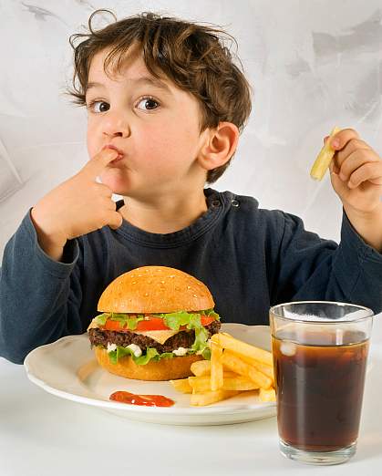 Photo of little boy eating fast food