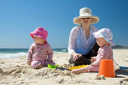 Photo of a woman and a baby wearing sun hats at the beach