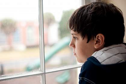 Photo of a young boy looking out a window