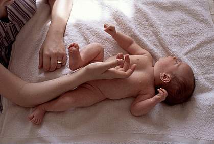 Photo of a mother’s hands touching her infant