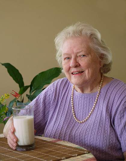 Photo of an older woman with a glass of milk.