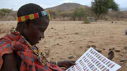 Hadza woman looking at a sheet with photos of other Hadza people.