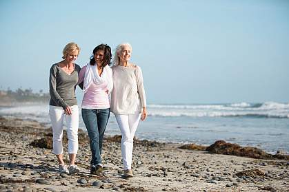 Three mature women walking on a windy beach.