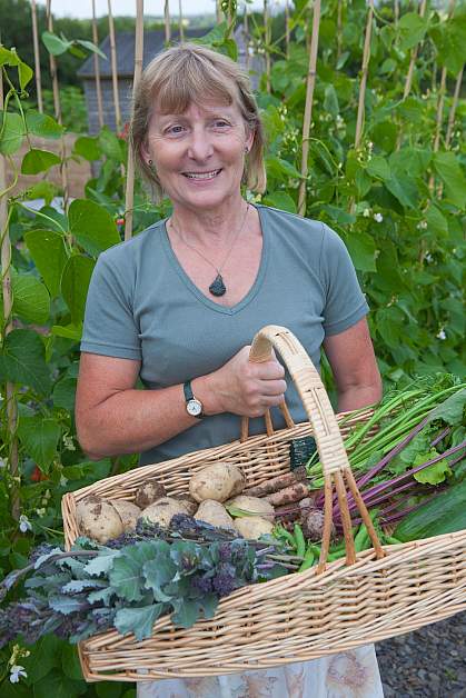 Happy woman with a wicker basket full of fresh vegetables.