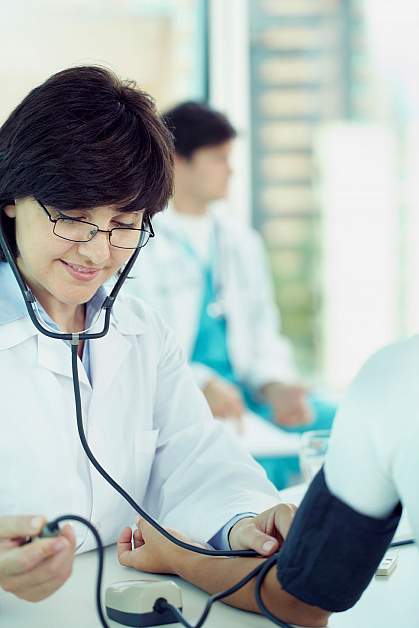 Female doctor checking patient’s blood pressure.