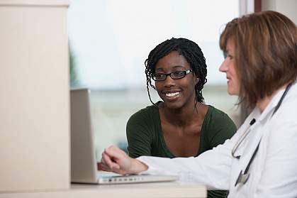 A woman and her doctor at a computer.