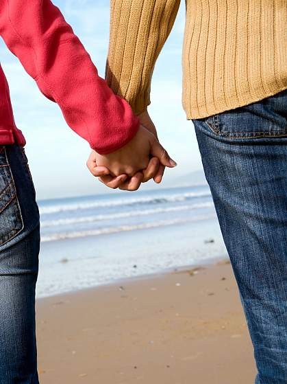 Couple holding hands on beach in winter