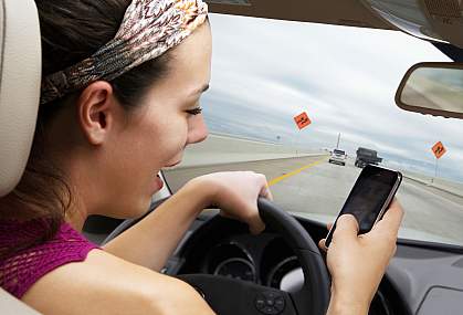 Young woman driving on highway while using smart phone.