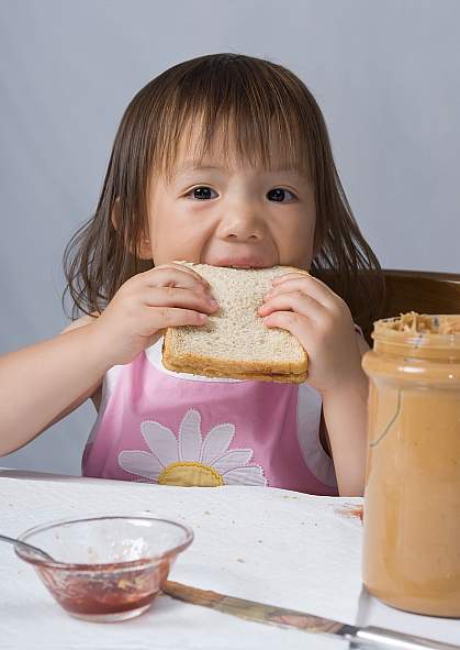 Girl eating a peanut butter sandwich.