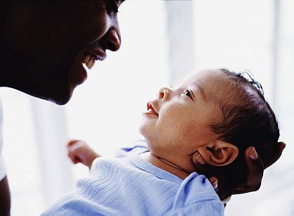 Father and newborn smiling at each other.