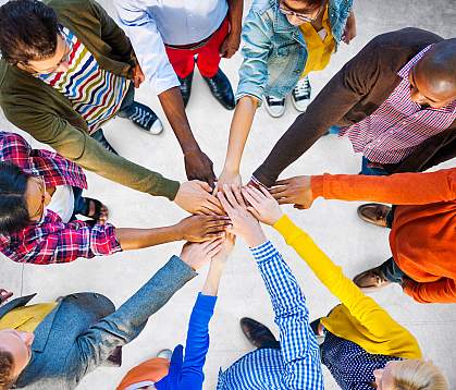 Circle of diverse people joining hands in the center.