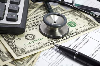 Stethoscope on dollar bills and medical forms.