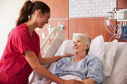 Nurse talking to an older woman in a hospital bed