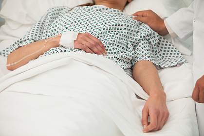 Heath care worker placing a hand on the shoulder of a sick patient in bed