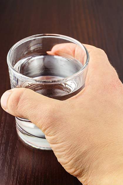 Hand gripping glass of water.