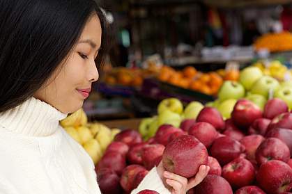 Young woman at store looking at apples