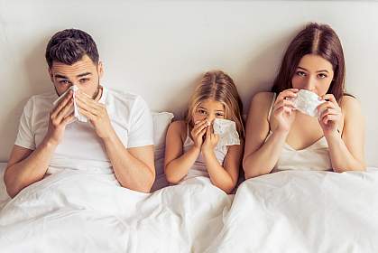 Family in bed together with colds