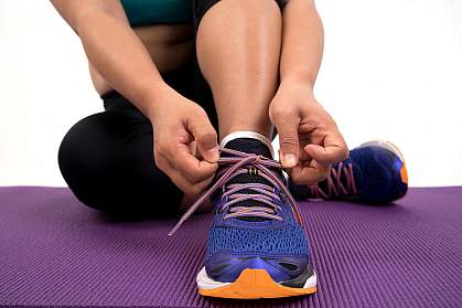 Overweight woman tying running shoe laces