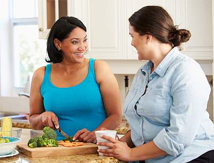 Two overweight women preparing vegetables in the kitchen