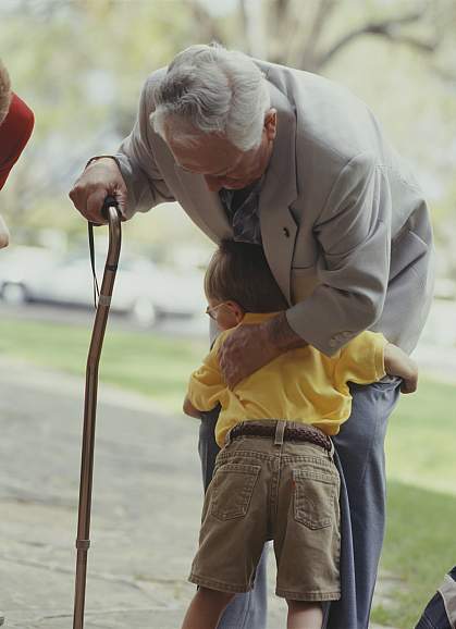 Grandfather with a cane hugged by a child