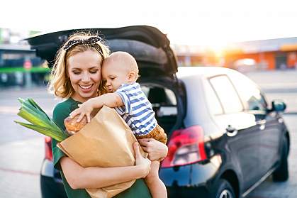 Young mother with baby boy carrying groceries to car