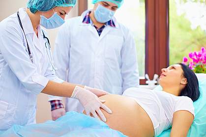 Doctor examines the abdomen of pregnant woman during childbirth