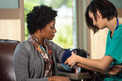 Health care worker setting up to take a woman’s blood pressure.