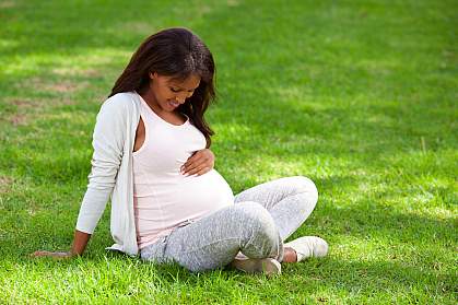 Pregnant woman sitting on green grass