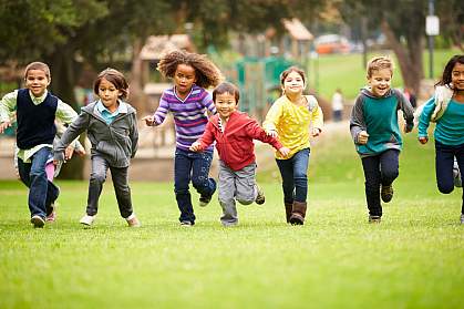 Group of children running over playground grass