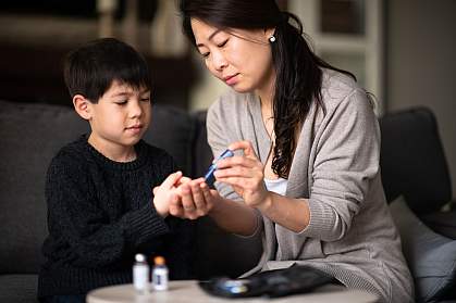 Mother helping son check blood sugar level