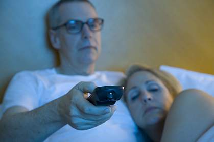 Sleepy couple watching TV in bed