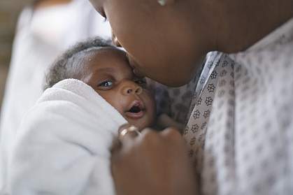 Young mother kissing her newborn on the forehead