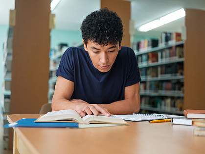 Student studying a book in the library