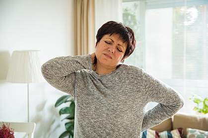 Mature woman holding her back and neck in pain