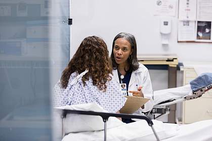 Female patient in a hospital bed talking to a doctor
